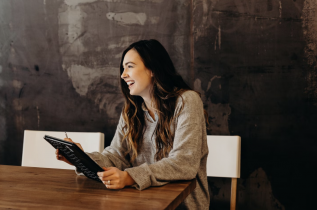 Smiling Woman Sitting at a Desk and on a Tablet